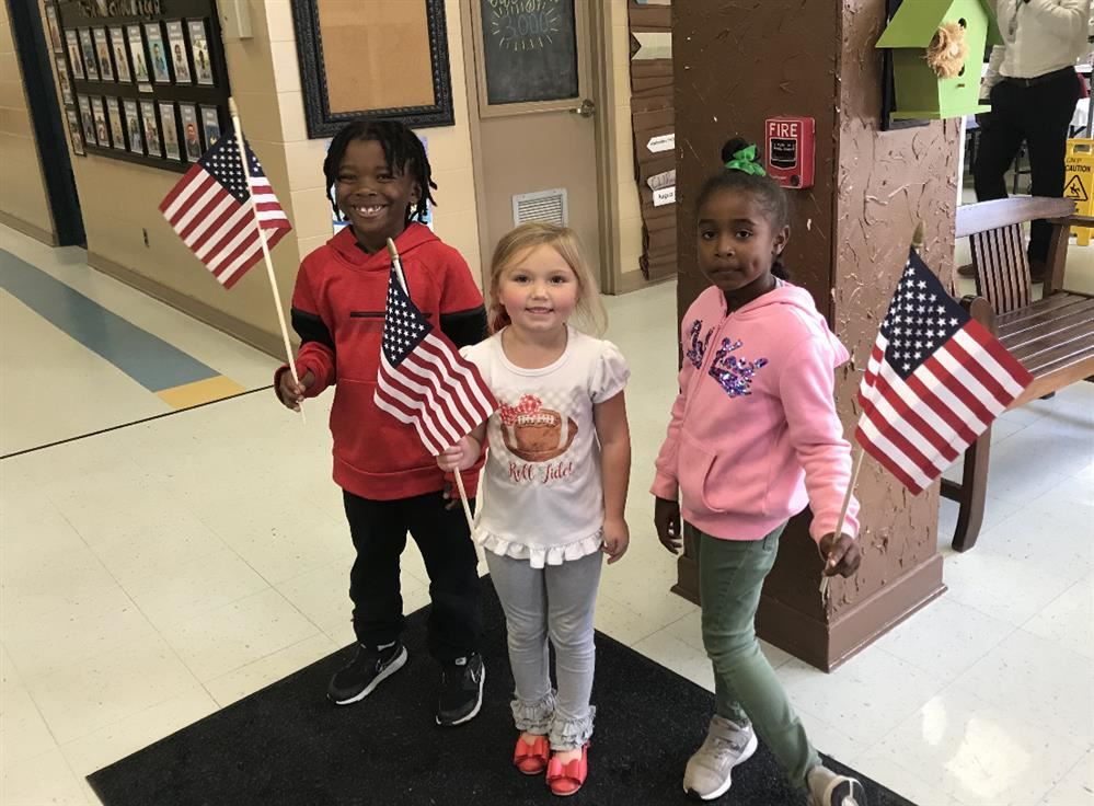 Three students holding American flags.