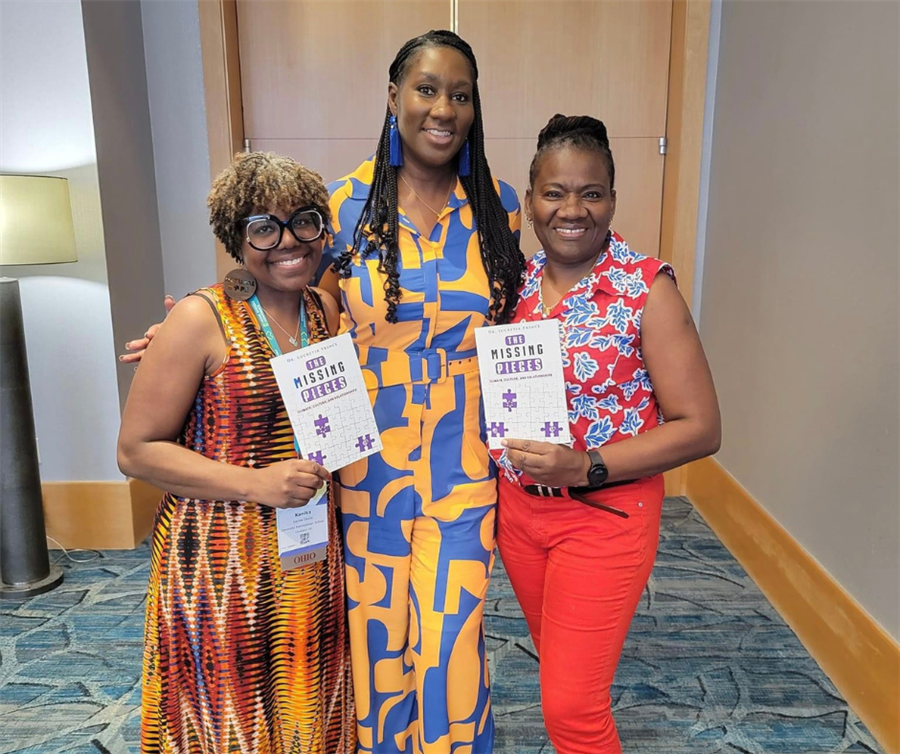 dr prince posing with educators holding books at model schools